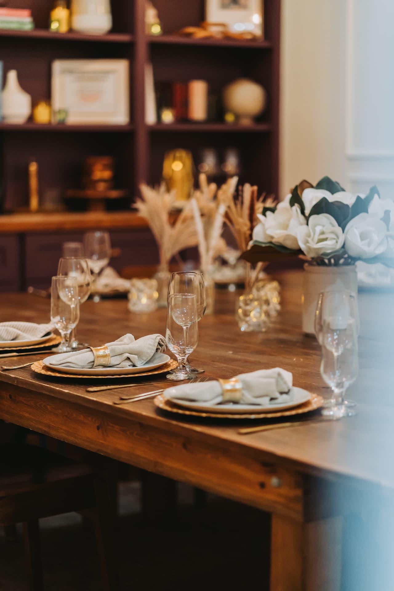 A private dining table set with china, glassware, and white flowers.